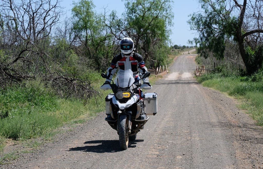 One of the bikers rides along a dirt road on their bike. 