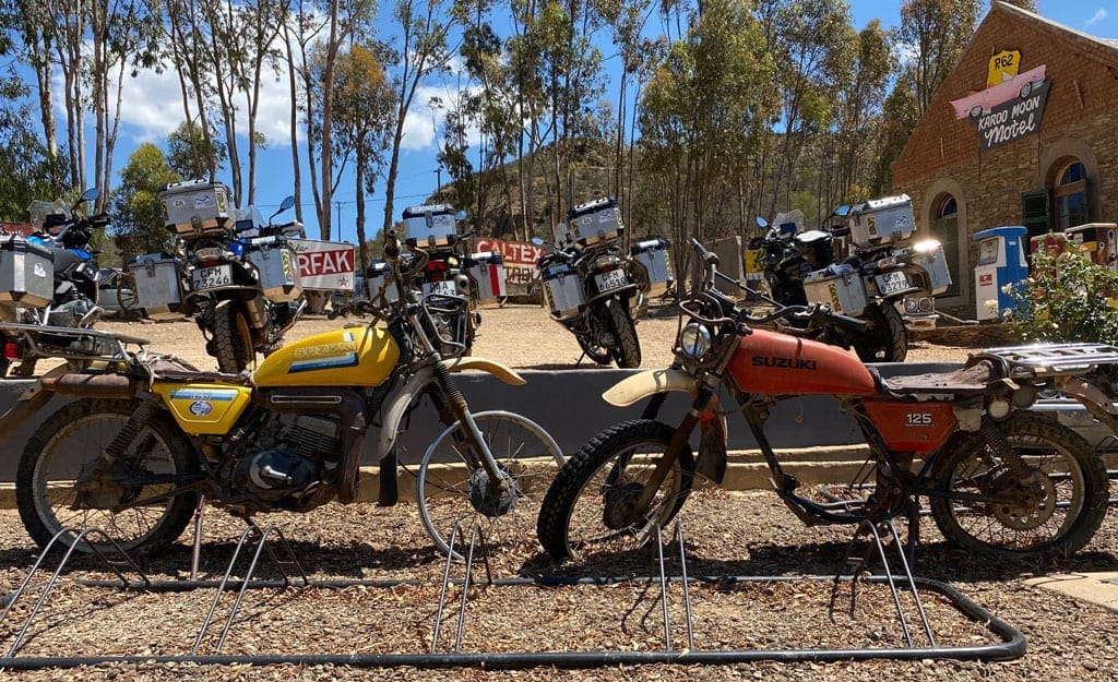 A couple of rusty, retro bikes  displayed outside a motel.