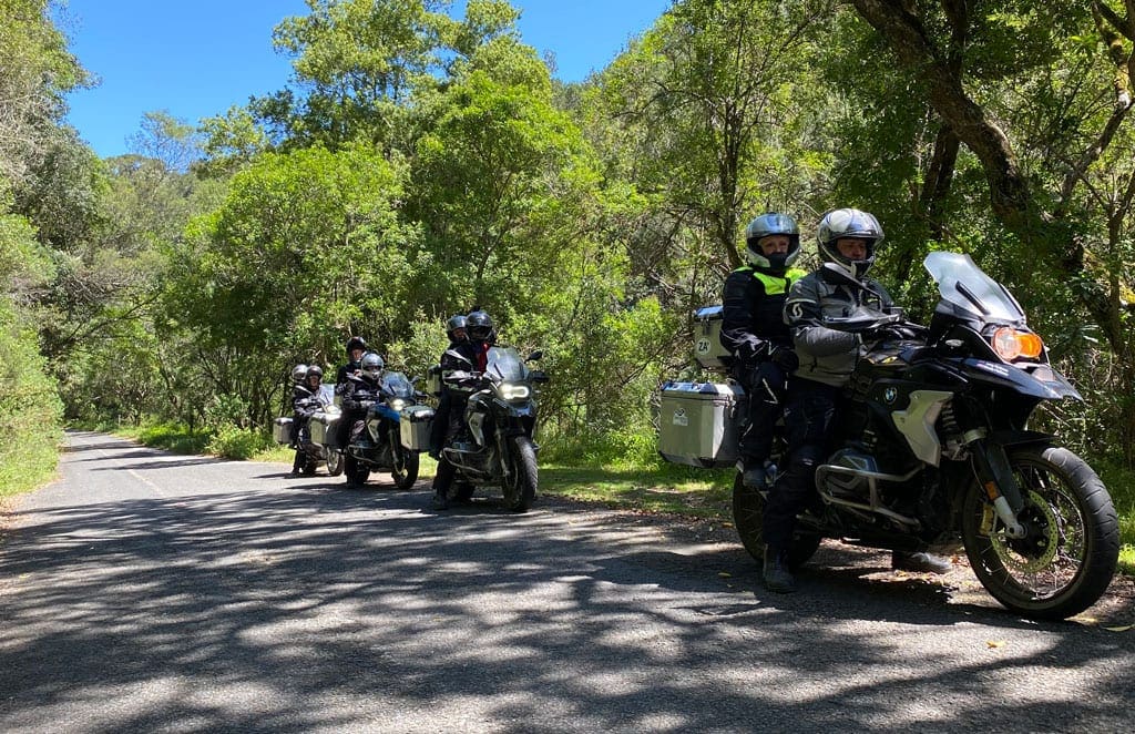 The group sit in pairs on their bikes as they ride along a forest road.
