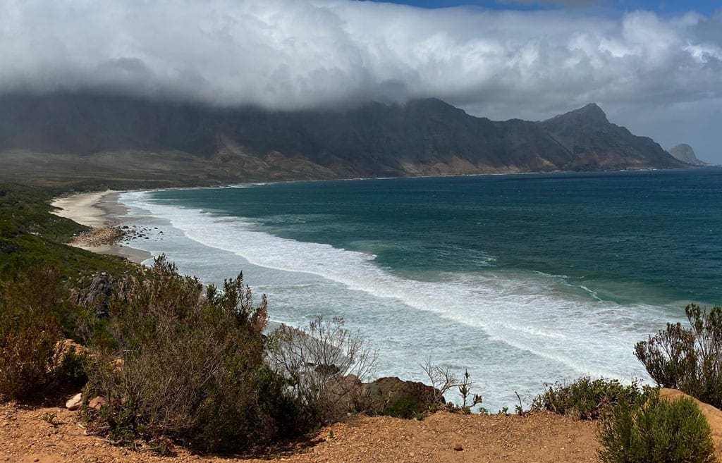 A view of the coast with the sea and misty mountains in the background. 