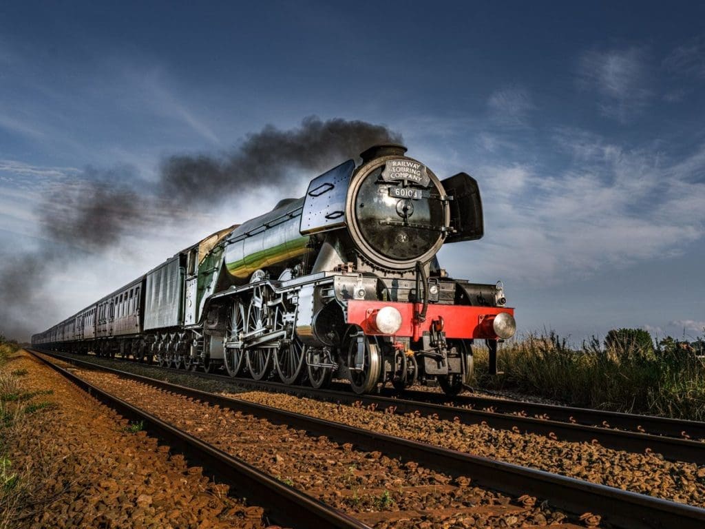 The Flying Scotsman steam train on the rails against a blue sky