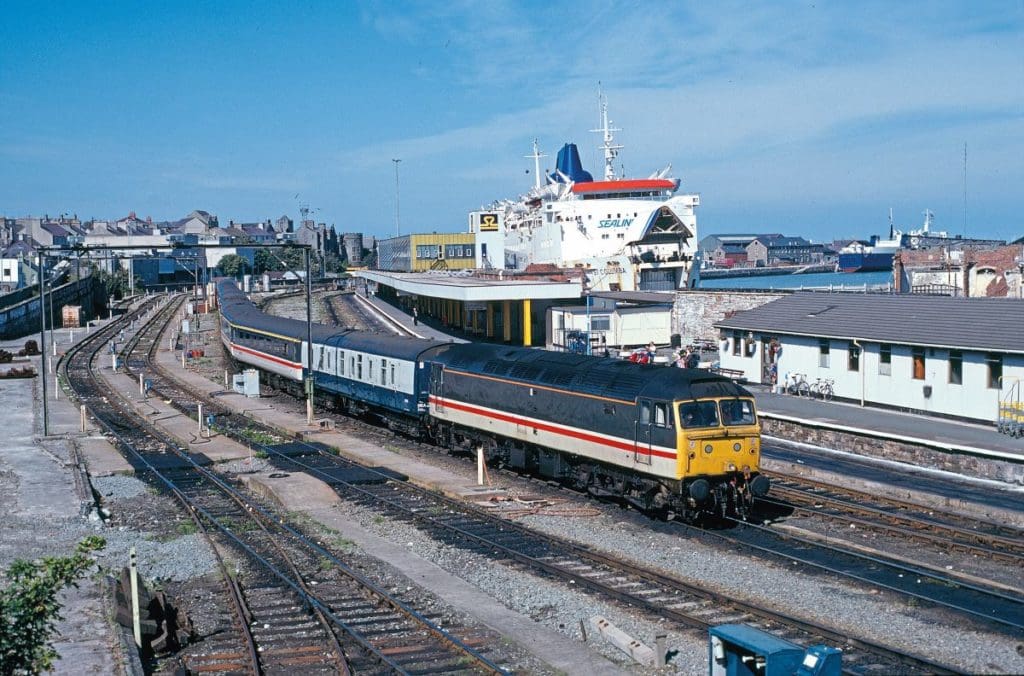 On September 3, 1989, in Intercity Executive livery, No. 47483 (original number 1637) is stabled at Holyhead, while a Sealink ferry to Ireland is berthed at the station terminal to the right.