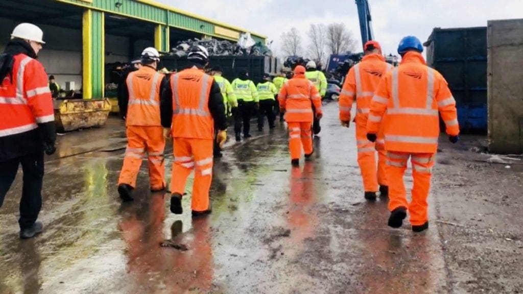 Members of Network rail in visibility jackets walk away in a group.