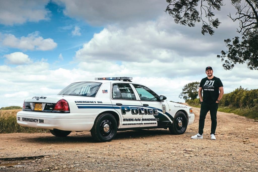Ewan stands beside his Crown Victoria American police car