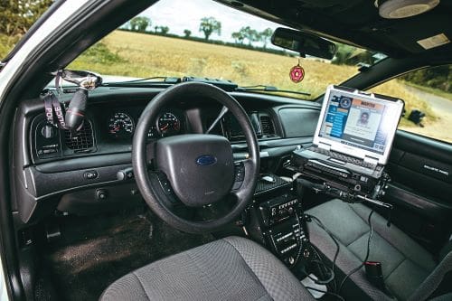 Crown Vic interior with steering wheel and open laptop.