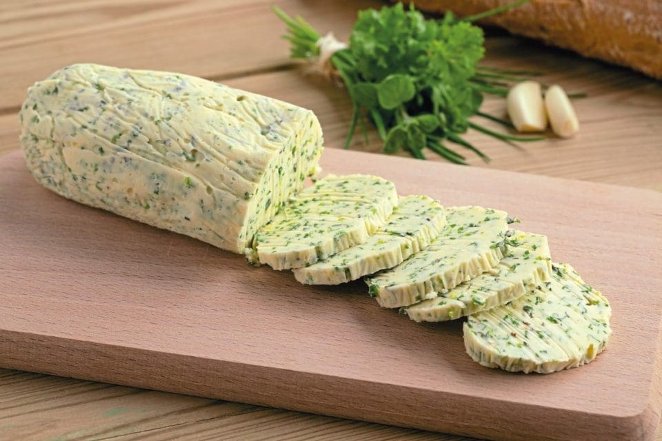 Sliced herb butter on a chopping board as a way of preserving herbs