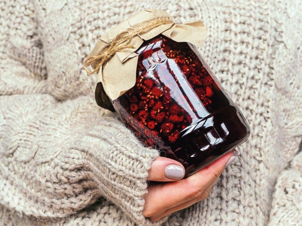 A hand holding a jar of homemade preserve 