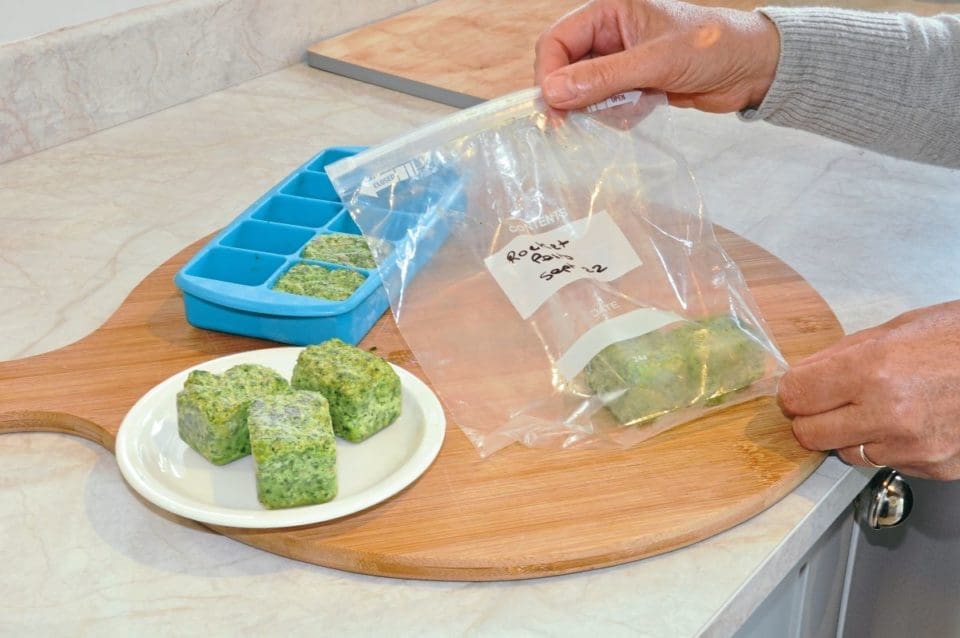 frozen cubes of rocket pesto being decanted into a freezer bag 