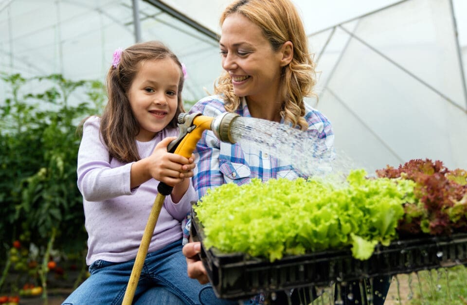 A mother and daughter watering homegrown vegetables