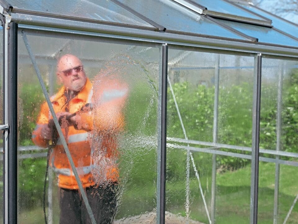 A man cleans a greenhouse