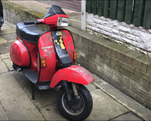 Red and black scooter on pavement, prior to restoration project