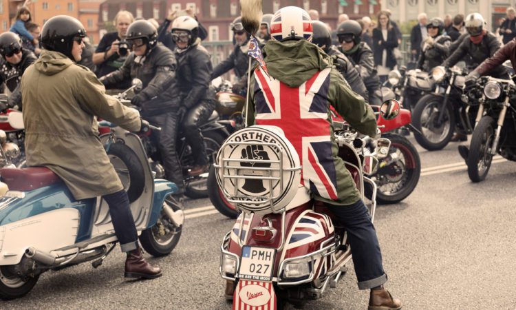 Mods wearing uk flag and rockers wearing leather clothes driving retro vespa scooters and mc at the Mods vs Rockers event