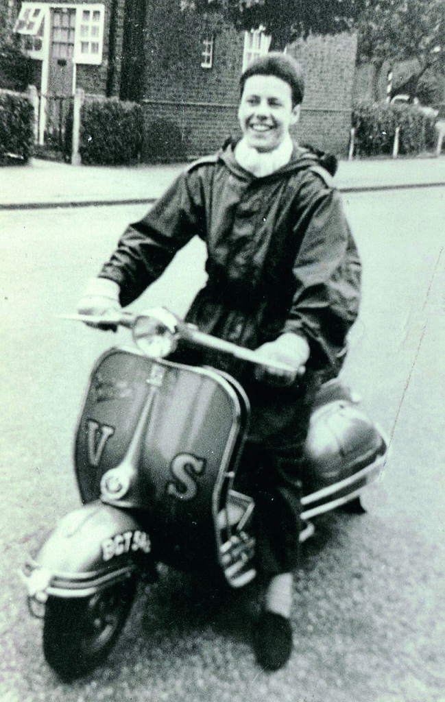 Ray: Me at 17, in 1964, with my Vespa Sportique. Cadillac crash bars and fashionable identification lettering on the front which was quite common. Note the Parka, white silk scarf, Levi jeans, and white socks to match the scarf and Hush Puppies. All this, topped off with the short-cropped mod-style haircut, which was essential because you did not want your hair looking out of place when cruising down the road… even in strong wind.