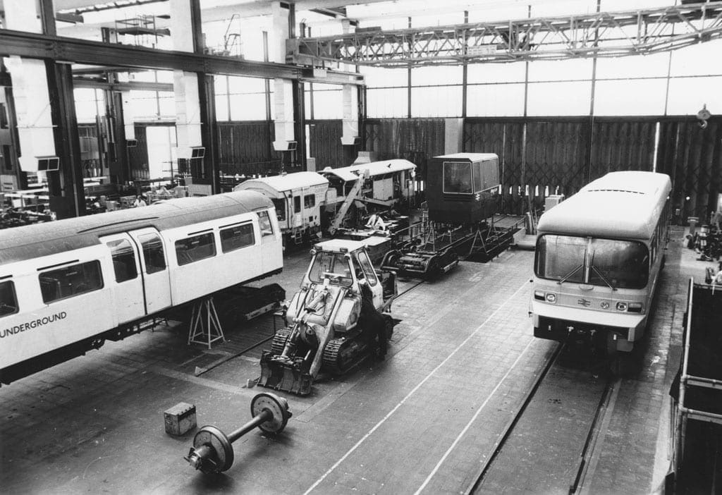 Black and white image of a warehouse with various train carriages. 