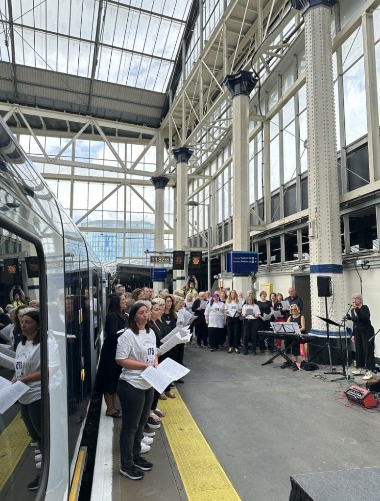 A choir of railway staff stand on a platform at Waterloo station as they perform