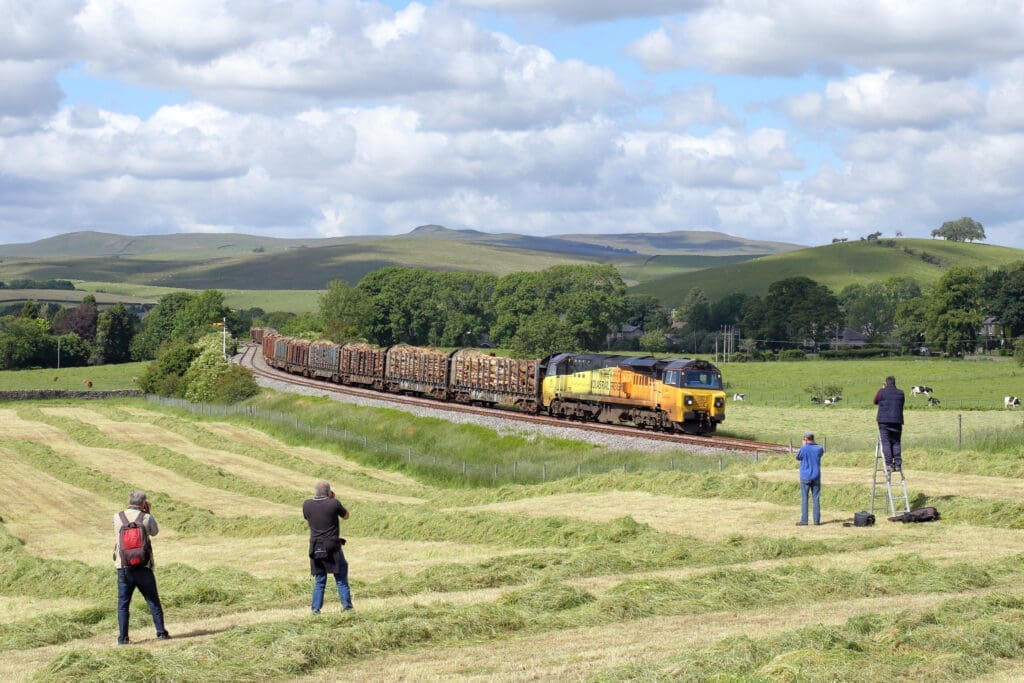 Getting height to get a better shot is nothing new; stepladders were the tool of choice toget some extra height for many years; but now poles can be used as well. Colas Rail’s70801 leaves Hellifield with 6J37, the 12.58 Carlisle-Chirk on June 21, 2019. AnthonyHicks