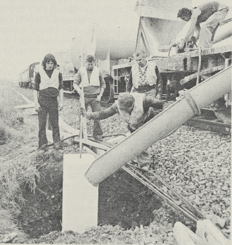 Mould being positioned in hole that has been drilled by equipment on a preceding boring train, before concrete is poured in to form the foundations for steelwork of the overhead catenary.