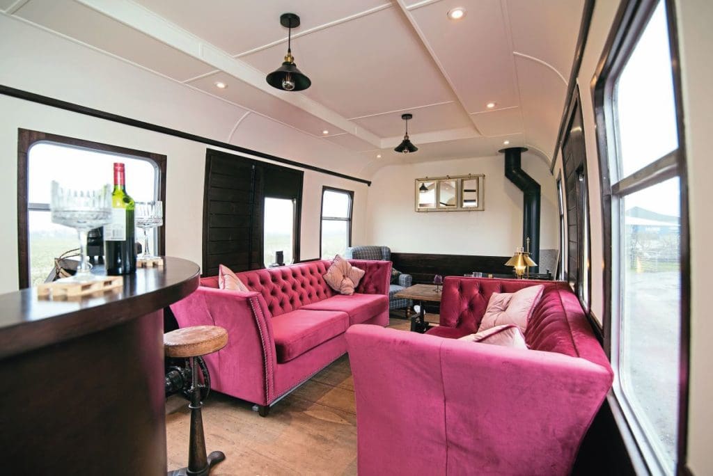 A view of the living room area, with two pink coaches and a bar.