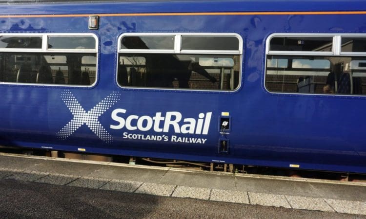 The side of a carriage of a blue ScotRail train, pulled against the platform of a station
