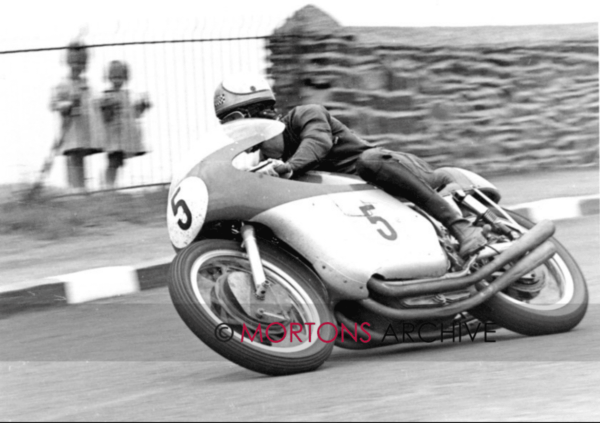 Black and white image of Mike Hailwood on a MV-4 500cc at Signpost Corner in the 1963 Isle of Man Senior TT