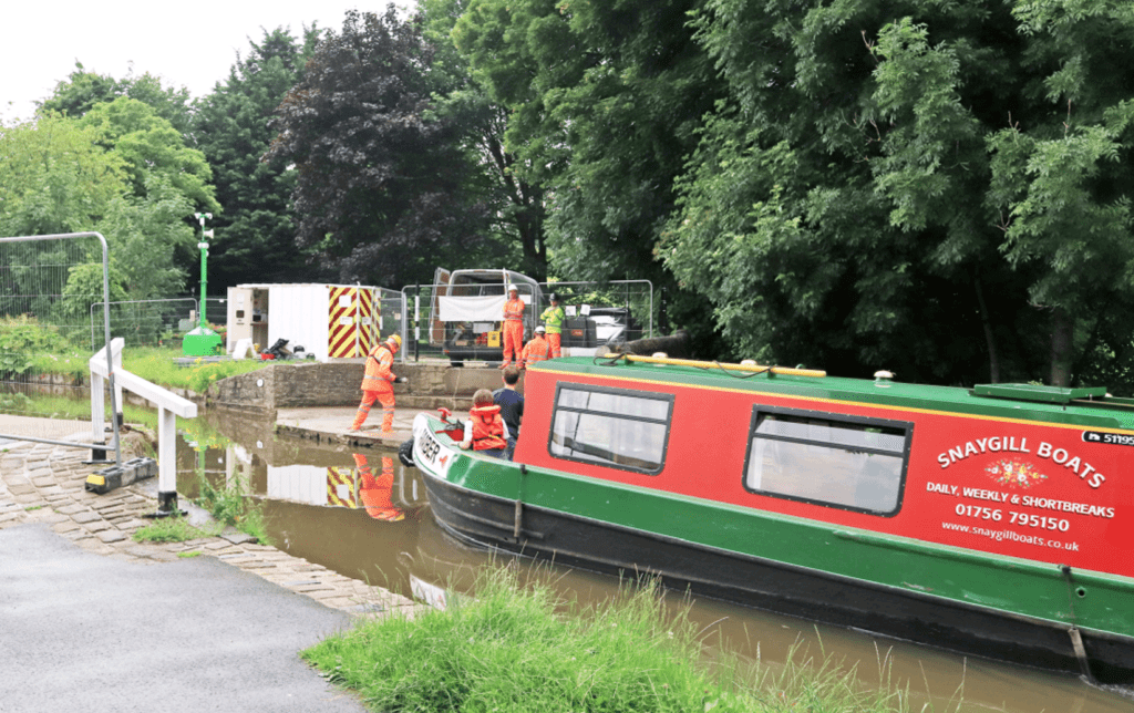 A hireboat passes contractors getting ready to replace the Gawflat swing bridge in Skipton.
