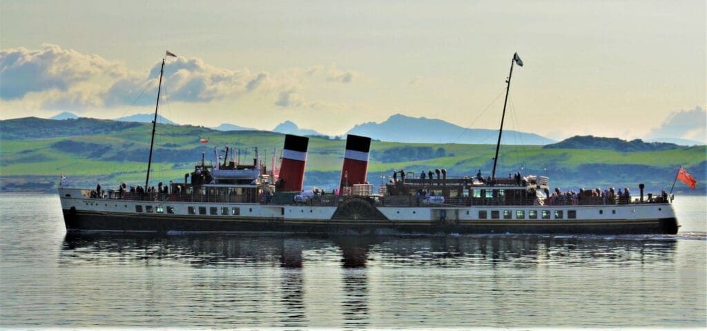 Sailing serenely, Waverley approaches Largs Pier, with Cumbrae and the mountains of Arran behind, to decant a full load of passengers on 22 August. Hugh Dougherty