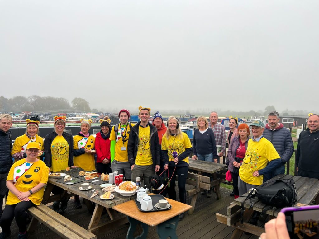 The walkers enjoy a welcome snack beside the marina. Holding the microphone right of centre is presenter Annabelle Amos and on her right are marine owners Debbie and John Skinner.