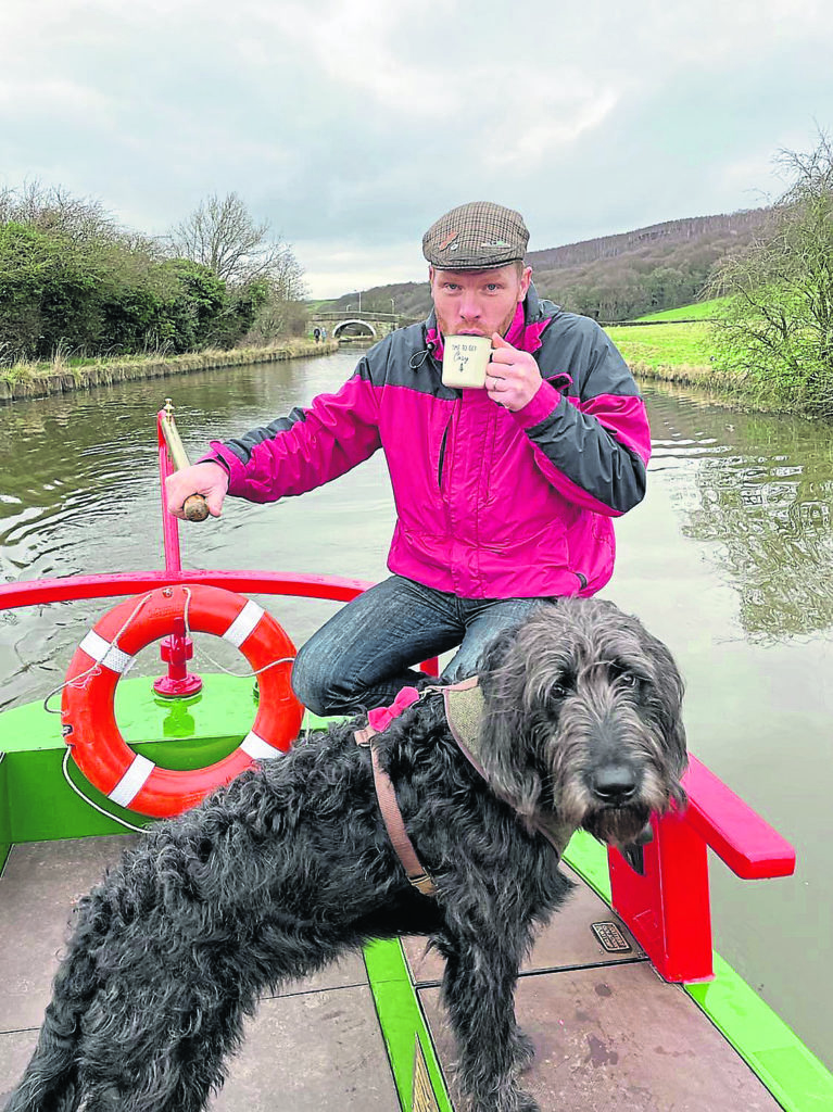Tim on the tiller with labradoodle Teddy.