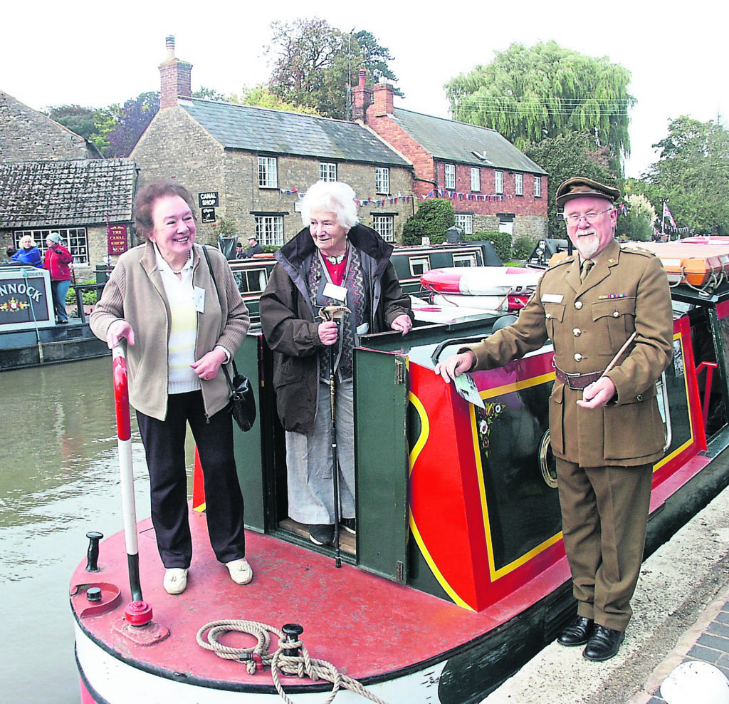 Happy times: Roy Sears as Captain Mainwaring with former Second World War ‘Idle Women’ canal volunteers Sonia Rolt, right, and Olga Kevelos. David Blagrove’s house, Wharf Cottage, is seen across the canal. 
