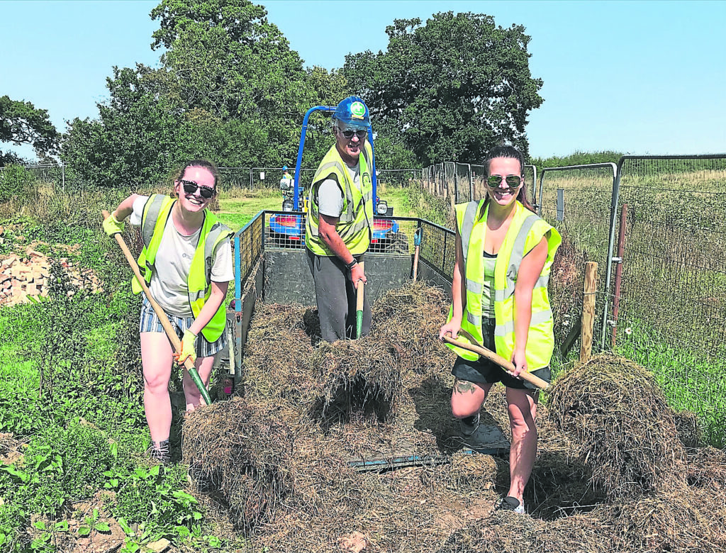 Good Energy volunteers Johanna Pettipher and Cherish Jackson laying mulch along the hedgerow with canal trust work party organiser Martin Palmer.