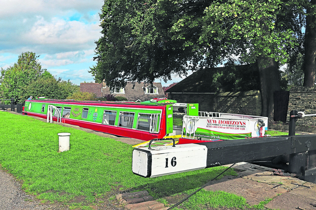 The New Horizons fully accessible community trip boat, run by volunteers of the Stockport Canal Boat Trust, using the top lock of the Marple flight as its base.