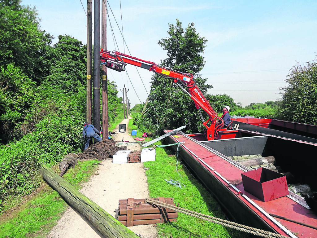 Hippo and a Hiab installing an electricity pole for UK Power Network on the River Lea.