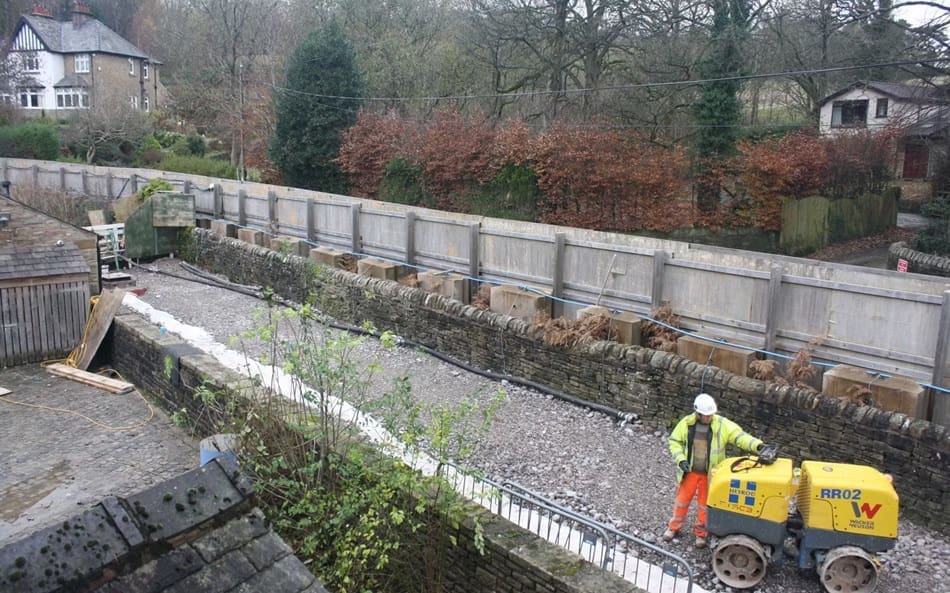 The section of the bypass channel behind the spillway structure is no longer needed, so it is being filled in and landscaped.