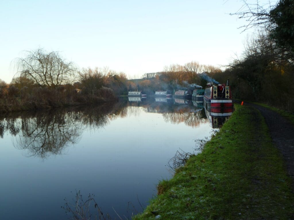 Narrowboats lining the Grand Union Canal near Bourne End fire their stoves for dinner as dusk settles. STEPHENRWALLI – CC BY-SA 2.0