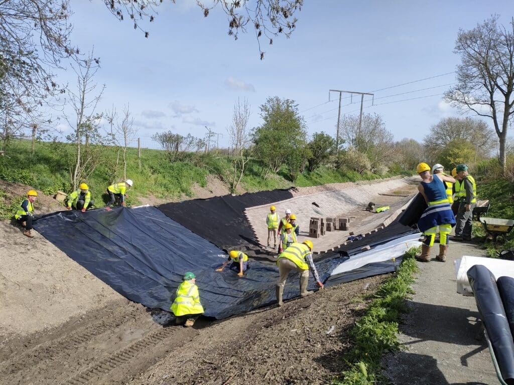 Shropshire Union Canal Society volunteers lining and blocking the canal channel.